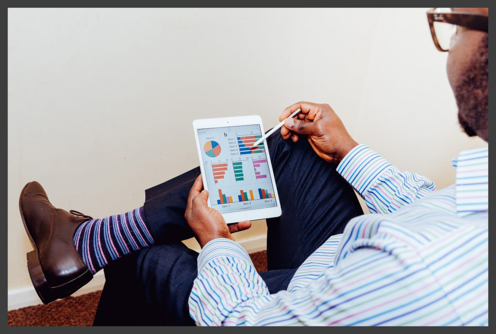 man reclining in a chair reviewing charts on a tablet