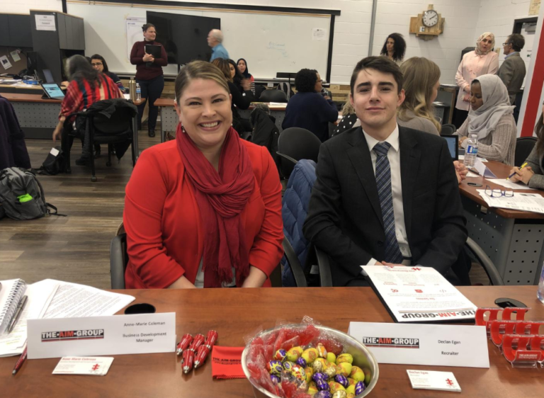 man and woman behind a dest for a job fair