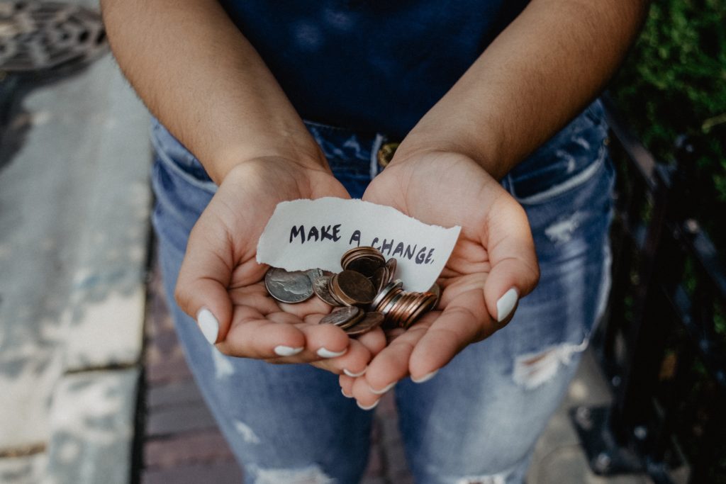 woman holding a note with "make a donation written on it" holding change